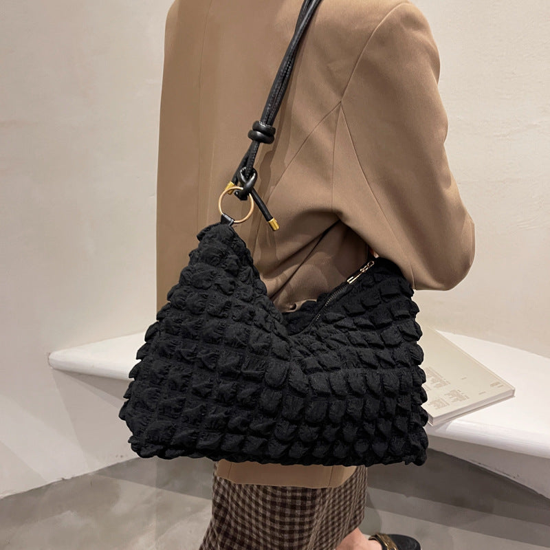 Sac porté épaule effet bulles noir, fermeture zippée, porté sur un blazer camel