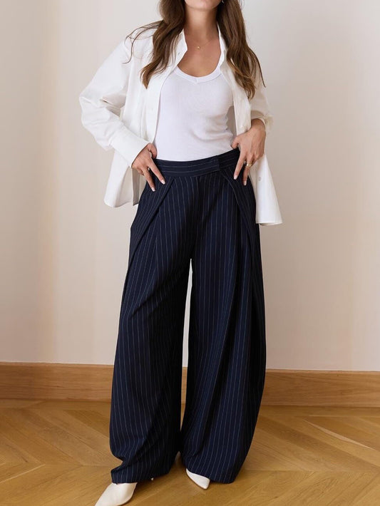 Pantalon large à pinces taille haute bleu marine à fines rayures, porté avec une chemise blanche