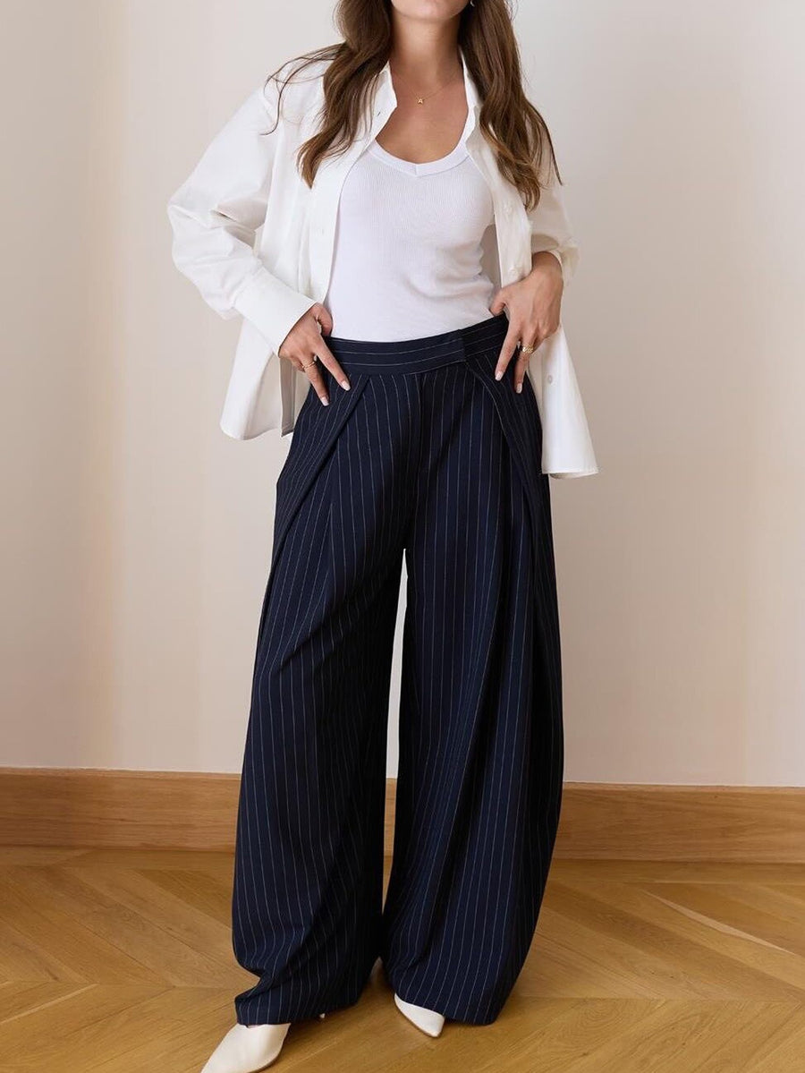 Pantalon large à pinces taille haute bleu marine à fines rayures, porté avec une chemise blanche