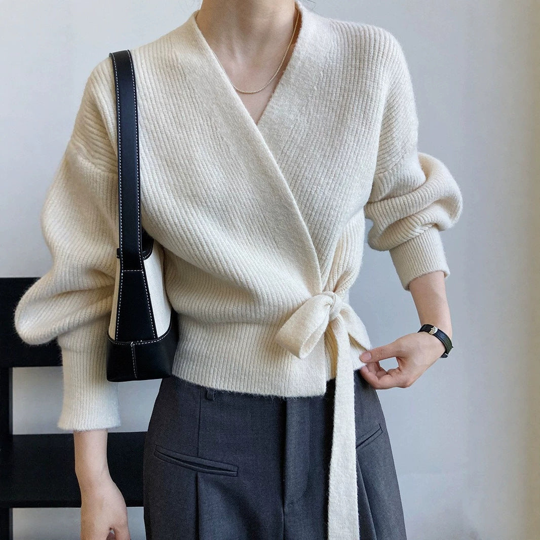 Gilet cache-cœur crème en maille côtelée, nœud à la taille, porté avec un pantalon large gris