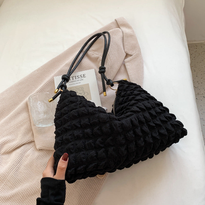 Sac effet bulles noir à anses nouées et finitions dorées, posé à plat