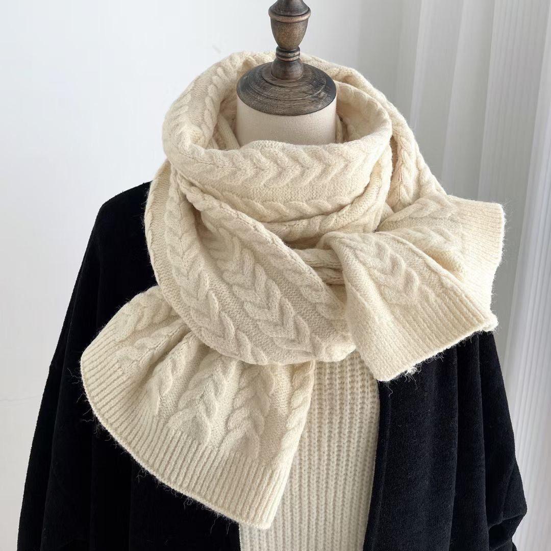 Écharpe en maille torsadée crème, enroulée sur un manteau noir